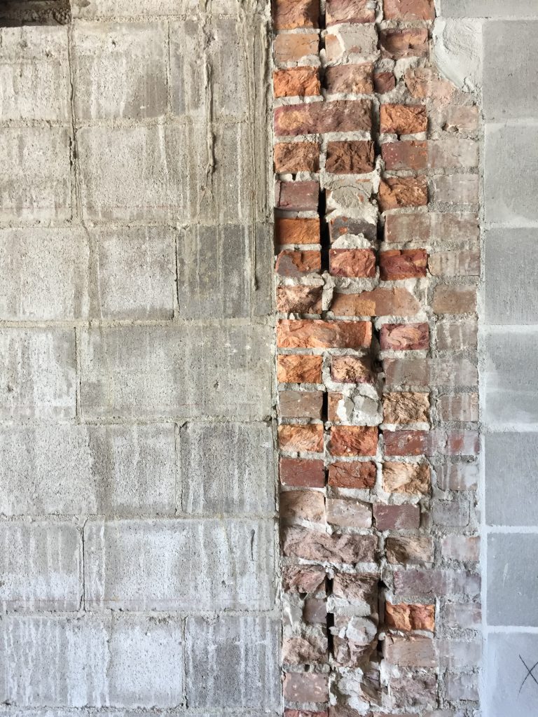 Selective demolition uncovering multi-wyth masonry walls